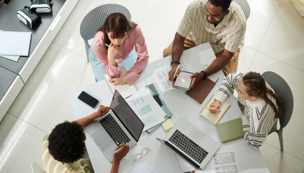 An embedded marketing team collaborating around a table, reviewing strategy and campaign plans together