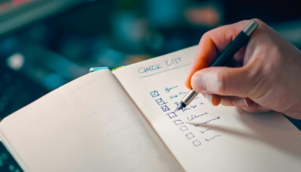 Hand writing a checklist in a notebook representing marketing tasks on a to-do list
